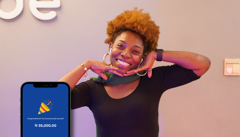 A smiling woman poses with her hands under her chin next to a phone displaying a congratulatory message for a payment of ₦35,000.00. The background is plain with part of a white logo visible.